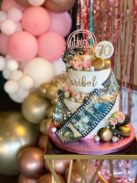 Tarta decorada 70 años carretes de fotos y flores naturales